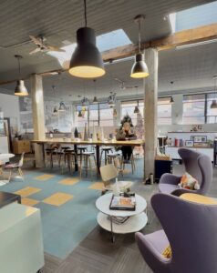 An open office space with a lady working containing lots of natural sky light